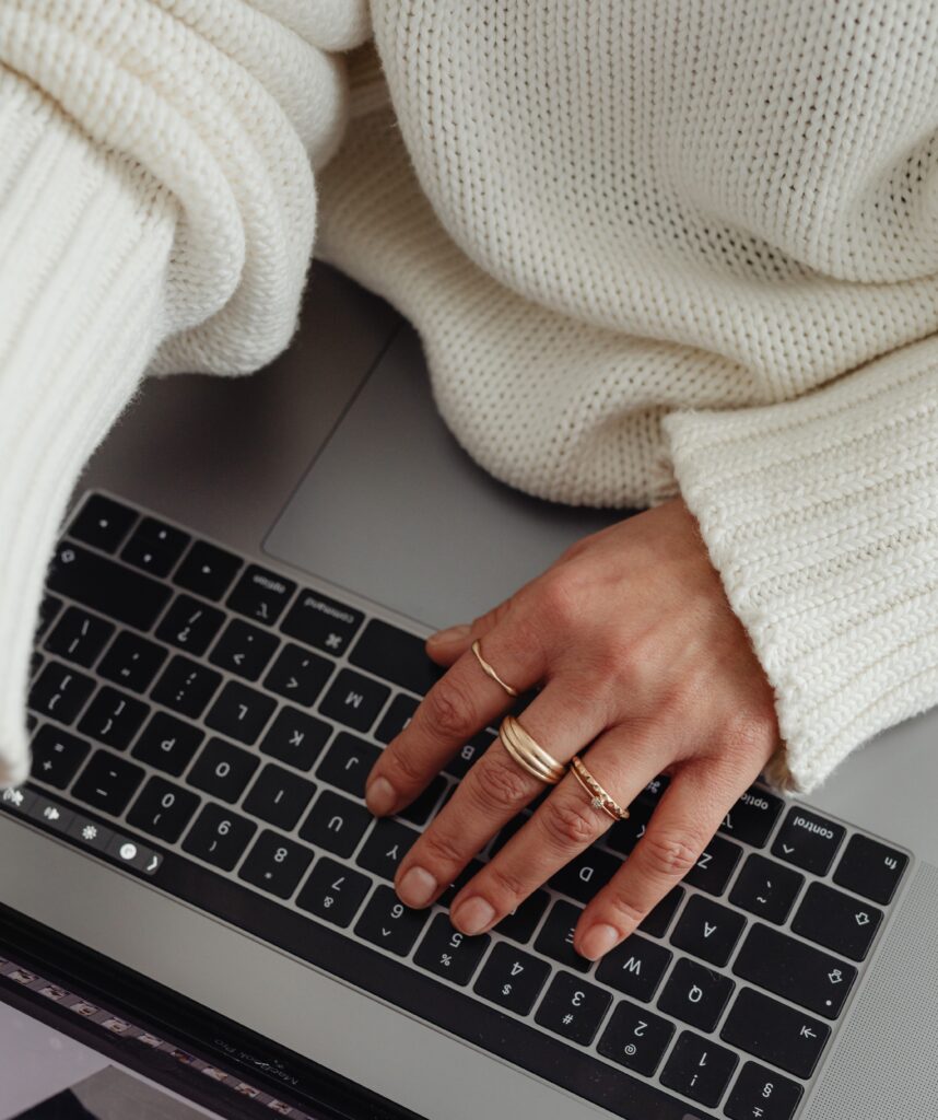 kaboompics woman in white sweater gold rings jewelry jeans laptop work 29446 mod